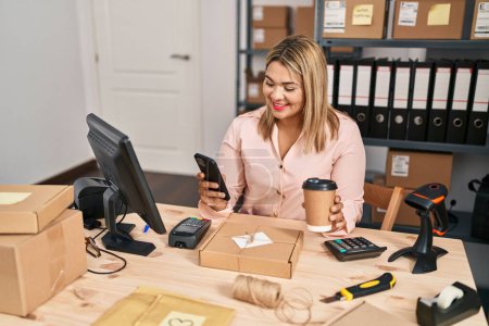 Téléchargez les photos : Jeune femme hispanique e-commerce travailleur d'affaires en utilisant smartphone et boire du café au bureau - en image libre de droit