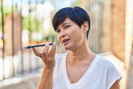 Téléchargez les photos : Moyen-âge femme chinoise parlant sur smartphone avec une expression sérieuse à la rue - en image libre de droit
