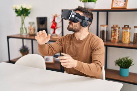 Photo for Young hispanic man playing video game using virtual reality glasses at home - Royalty Free Image