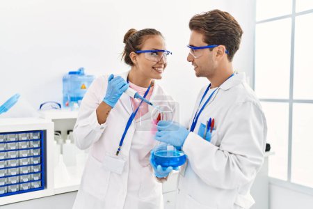 Photo for Man and woman wearing scientist uniform using pipette and test tube working at laboratory - Royalty Free Image