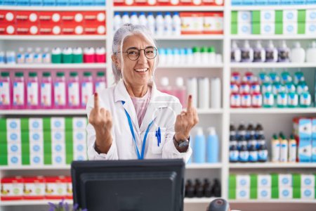 Photo for Middle age woman with tattoos working at pharmacy drugstore showing middle finger doing fuck you bad expression, provocation and rude attitude. screaming excited - Royalty Free Image