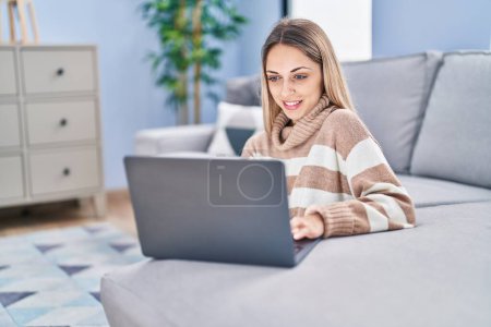 Photo for Young woman using laptop sitting on floor at home - Royalty Free Image