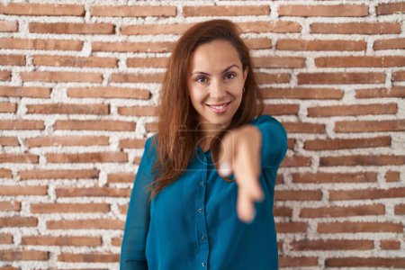 Téléchargez les photos : Femme brune debout au-dessus du mur de briques souriant amical offrant poignée de main comme salutation et accueil. entreprise prospère. - en image libre de droit