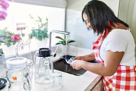 Photo for Hispanic brunette woman washing dishes at the kitchen - Royalty Free Image