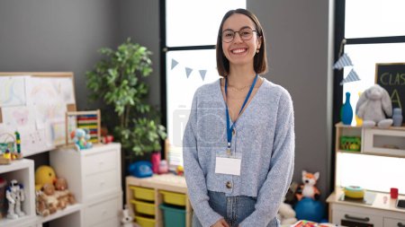 Téléchargez les photos : Young beautiful hispanic woman teacher smiling confident standing at kindergarten - en image libre de droit
