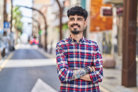 Foto de Young hispanic man smiling confident standing with arms crossed gesture at street - Imagen libre de derechos