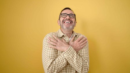 Téléchargez les photos : Homme du Moyen Age souriant confiant se serrant dans ses bras sur fond jaune isolé - en image libre de droit