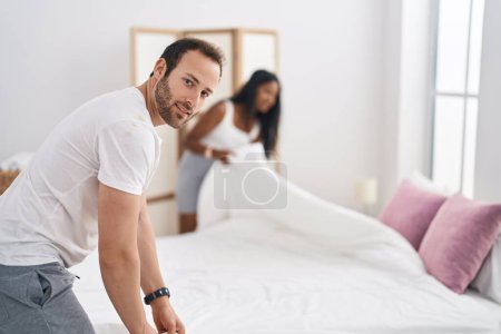 Photo for Man and woman interracial couple making bed at bedroom - Royalty Free Image
