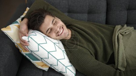 Foto de Joven hispano tumbado en un sofá durmiendo en casa - Imagen libre de derechos