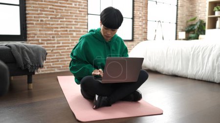 Photo for Young chinese woman using laptop sitting on floor at bedroom - Royalty Free Image