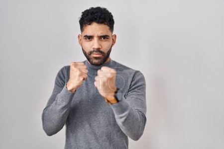Photo for Hispanic man with beard standing over white background ready to fight with fist defense gesture, angry and upset face, afraid of problem - Royalty Free Image