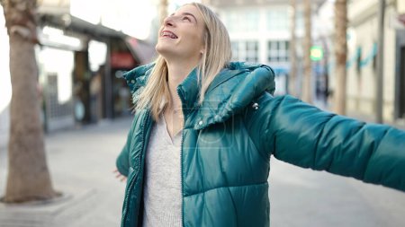 Téléchargez les photos : Young blonde woman smiling happy with open arms at street - en image libre de droit