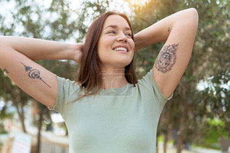 Téléchargez les photos : Jeune belle femme souriante confiante détendue avec les mains sur la tête au parc - en image libre de droit