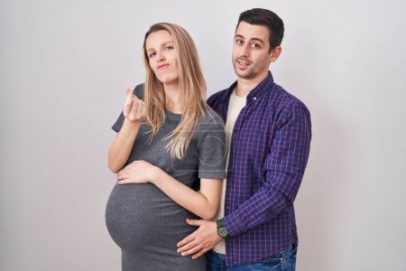 Photo for Young couple expecting a baby standing over white background doing money gesture with hands, asking for salary payment, millionaire business - Royalty Free Image