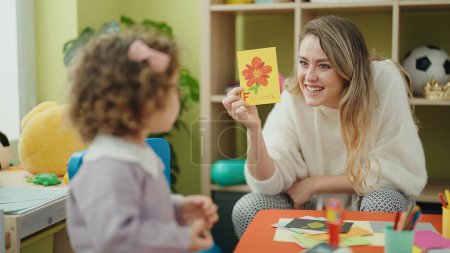 Photo for Teacher and toddler sitting on table having language lesson at kindergarten - Royalty Free Image