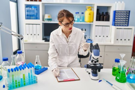 Foto de Joven mujer caucásica vistiendo uniforme científico sosteniendo tubo de ensayo en laboratorio - Imagen libre de derechos