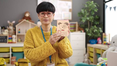 Téléchargez les photos : Young chinese woman preschool teacher having vocabulary lesson at kindergarten - en image libre de droit