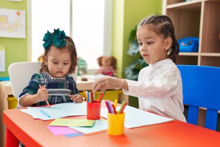 Photo for Brother and sister students sitting on table drawing on paper at kindergarten - Royalty Free Image