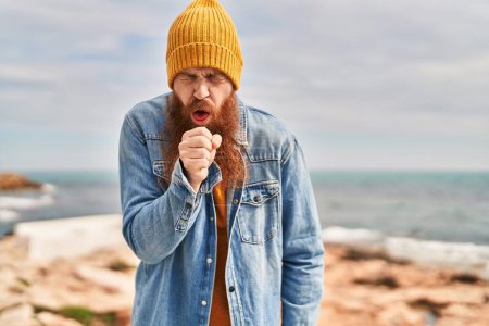 Foto de Young redhead man coughing at seaside - Imagen libre de derechos