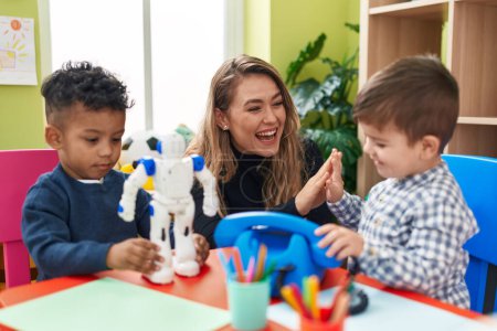 Foto de Profesor con niños sentados en la mesa jugando con juguetes en el jardín de infantes - Imagen libre de derechos