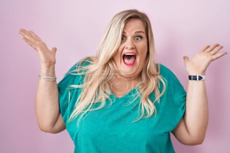 Téléchargez les photos : Caucasian plus size woman standing over pink background celebrating crazy and amazed for success with arms raised and open eyes screaming excited. winner concept - en image libre de droit