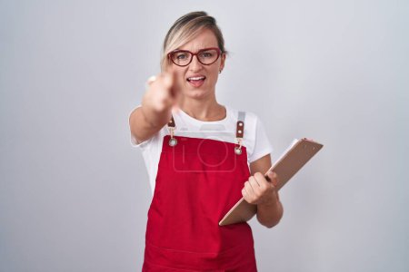 Photo for Young blonde woman wearing waiter uniform holding clipboard pointing displeased and frustrated to the camera, angry and furious with you - Royalty Free Image