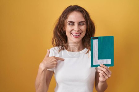 Photo for Beautiful brunette woman holding l sign for new driver pointing finger to one self smiling happy and proud - Royalty Free Image