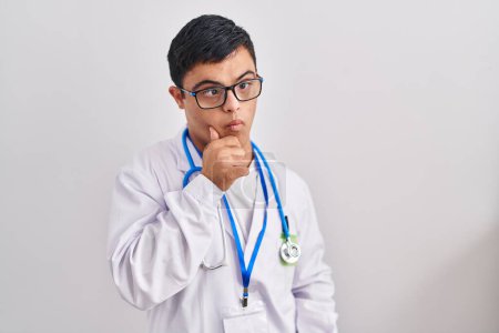 Photo for Young hispanic man with down syndrome wearing doctor uniform and stethoscope serious face thinking about question with hand on chin, thoughtful about confusing idea - Royalty Free Image