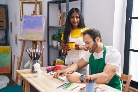 Photo for Man and woman artist couple drawing on notebook and drinking coffee at art studio - Royalty Free Image