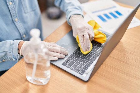 Photo for Young hispanic man business worker cleaning laptop at office - Royalty Free Image
