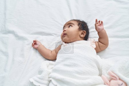 Foto de Bebé afroamericano acostado en la cama con expresión relajada en el dormitorio - Imagen libre de derechos