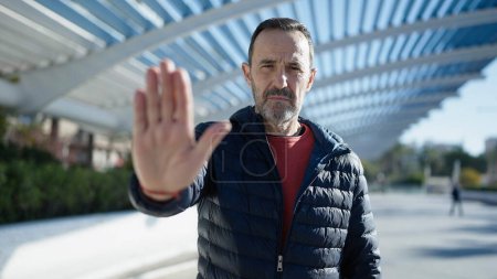 Téléchargez les photos : Middle age man doing stop gesture with hand at park - en image libre de droit