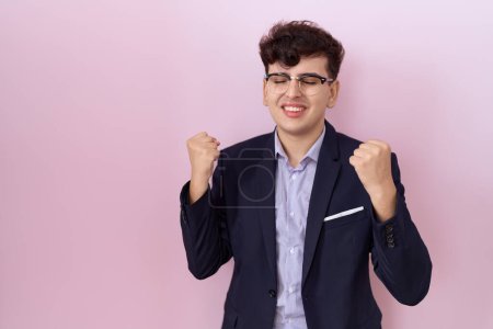 Foto de Young non binary man with beard wearing suit and tie very happy and excited doing winner gesture with arms raised, smiling and screaming for success. celebration concept. - Imagen libre de derechos