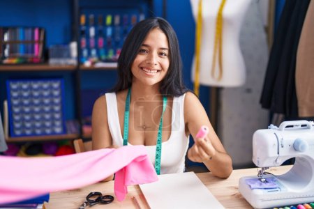 Photo for Young hispanic woman tailor smiling confident holding cloth and thread at sewing studio - Royalty Free Image