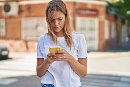 Téléchargez les photos : Young blonde girl using smartphone at street - en image libre de droit