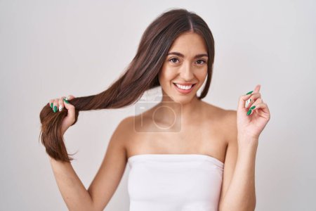 Téléchargez les photos : Young hispanic woman holding hair with hand smiling happy pointing with hand and finger to the side - en image libre de droit
