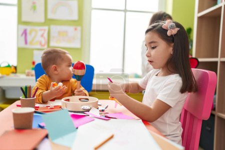 Photo for Group of kids preschool students sitting on table playing maraca and making handcrafts at kindergarten - Royalty Free Image