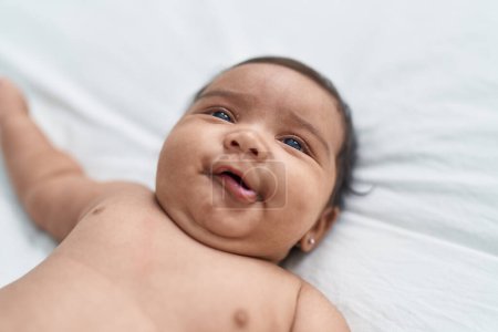 Téléchargez les photos : African american baby smiling confident lying on bed at bedroom - en image libre de droit