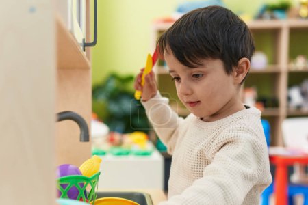 Téléchargez les photos : Adorable hispanic boy playing with play kitchen standing at kindergarten - en image libre de droit