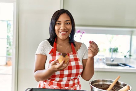 Téléchargez les photos : Hispanic brunette woman preparing chocolate muffins at the kitchen - en image libre de droit