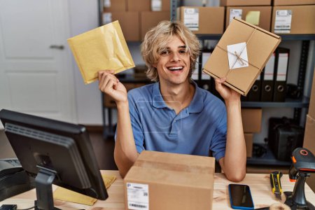 Téléchargez les photos : Young man working at small business ecommerce holding packages smiling with a happy and cool smile on face. showing teeth. - en image libre de droit