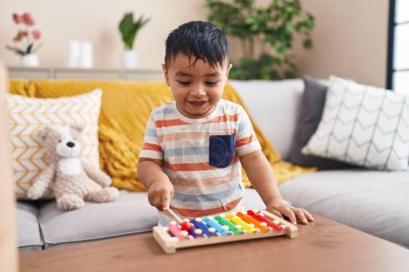 Photo for Adorable hispanic toddler playing xylophone standing at home - Royalty Free Image