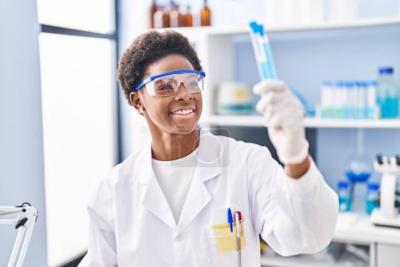 Foto de African american woman wearing scientist uniform holding test tubes at laboratory - Imagen libre de derechos
