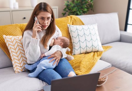 Photo for Mother and son breastfeeding baby teleworking at home - Royalty Free Image