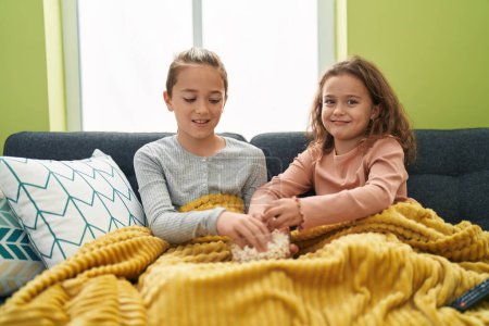 Téléchargez les photos : Deux enfants mangent du pop-corn en regardant un film à la maison - en image libre de droit