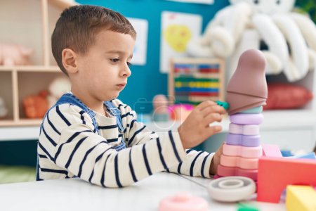 Foto de Adorable caucasian boy sitting on table playing with toys at kindergarten - Imagen libre de derechos