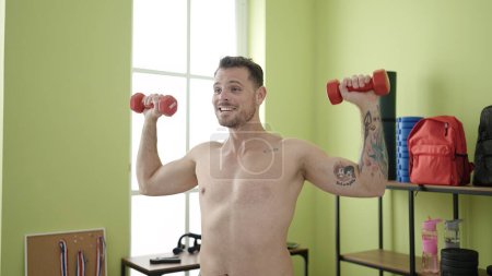 Foto de Young caucasian man training using weights at sport center - Imagen libre de derechos