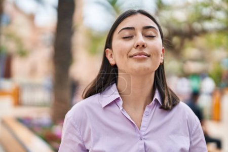 Téléchargez les photos : Jeune femme hispanique souriant respiration confiante au parc - en image libre de droit