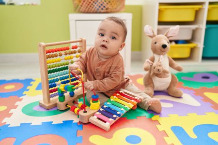 Photo for Adorable hispanic toddler playing xylophone sitting on floor at kindergarten - Royalty Free Image