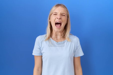 Photo for Young caucasian woman wearing casual blue t shirt angry and mad screaming frustrated and furious, shouting with anger. rage and aggressive concept. - Royalty Free Image